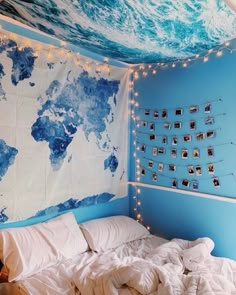 an unmade bed in a room with a world map on the wall above it