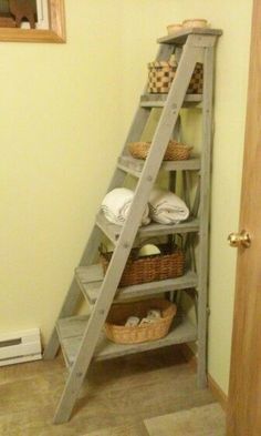 a ladder leaning up against a wall with baskets on it and towels in the basket below