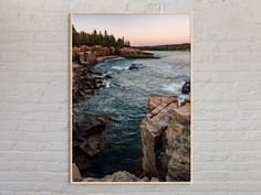 an image of the ocean and rocks in front of a white brick wall with a wooden frame