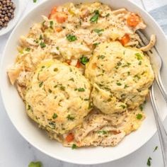 a white bowl filled with chicken pot pies next to some peas and corian seeds