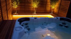 an outdoor hot tub in the middle of a wooden decked area with lights on it