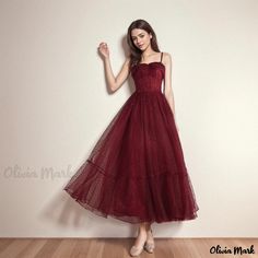 a woman in a red dress standing on a wooden floor with her hand up to the side