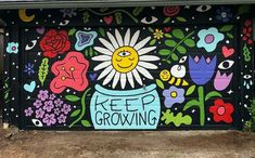 a painted mural on the side of a garage door with flowers and bees around it