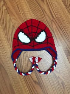 a knitted spiderman hat on top of a wooden floor