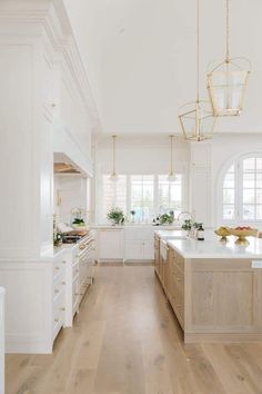 a large kitchen with white cabinets and wood flooring, along with an island in the middle