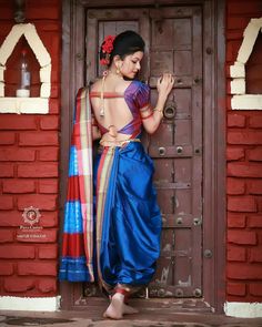 a woman standing in front of a door wearing a blue sari and red scarf