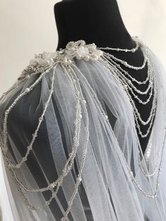 the back of a veil with pearls and chains on it