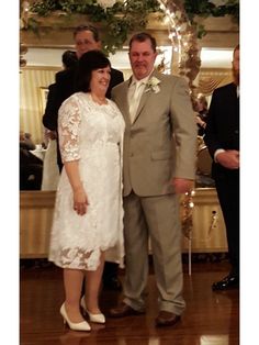 a man and woman standing next to each other in front of a table full of people