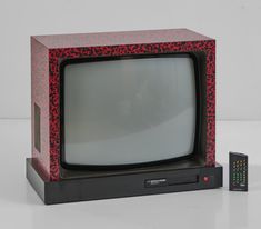 an old fashioned television sitting on top of a white table next to a remote control