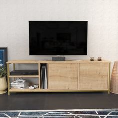 a flat screen tv sitting on top of a wooden entertainment center next to a plant