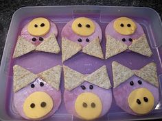 some little pigs with cheese and crackers in their mouths are on a purple tray