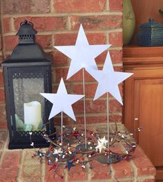 three white stars on top of a table next to a lantern