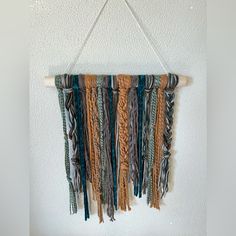 a wall hanging made out of different colored yarns on a wooden stick and rope