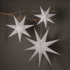 three white paper stars hanging from a twig