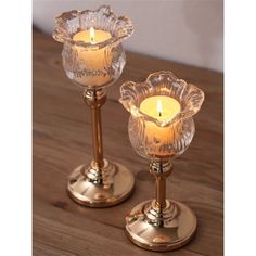 two clear glass candlesticks sitting on top of a wooden table