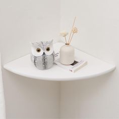 an owl figurine sitting on top of a white shelf next to a book