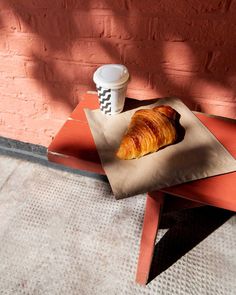 a croissant sitting on top of a table next to a cup