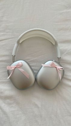 a pair of headphones laying on top of a white bed covered in pink ribbon