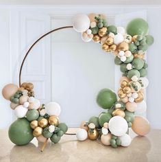 a balloon arch with gold, white and green balloons in the shape of a circle