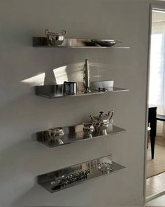 three shelves with silver dishes on them in a living room next to a dining room table