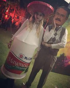 a man standing next to a woman wearing a fake hat and holding a giant bottle