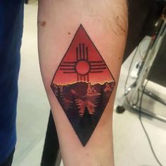 a person with a tattoo on their arm that has mountains and trees in the background