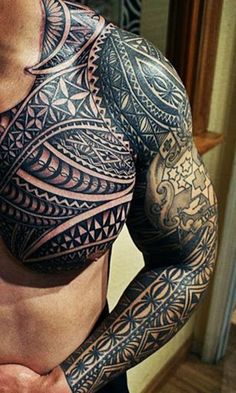 the back of a man's shoulder with intricate tattoos on his arm and chest