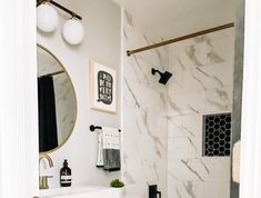 a white bathroom with marble tile and gold fixtures