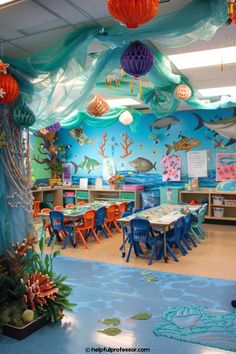 an ocean themed classroom with blue walls and colorful decorations on the ceiling, along with tables and chairs