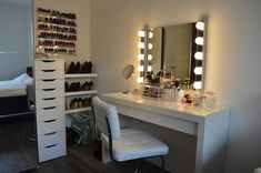 a room with a vanity, stools and lights on it in front of a mirror