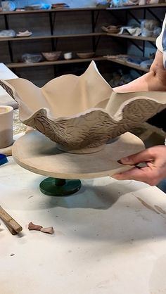 a person working on a sculpture in a pottery studio with other tools and supplies nearby