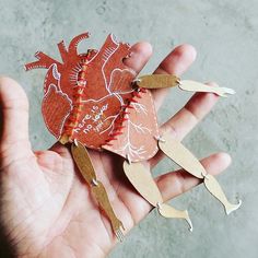 someone is holding up some paper cutouts in their hand with the shape of a heart on it