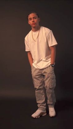 a man standing in front of a black background with his hands in his pockets and looking at the camera