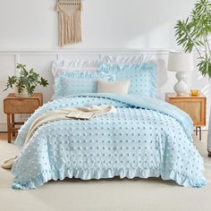 a bed covered in blue polka dot comforter and pillows with white trimmings