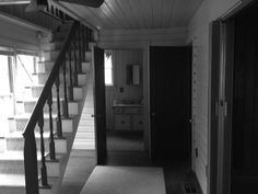 an empty hallway with stairs leading up to the second floor and another room in the background