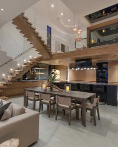 a living room filled with furniture next to a stair case and wooden table surrounded by chairs