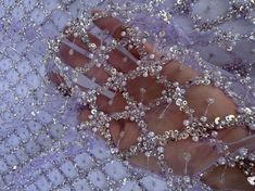 a person's foot covered in beads and sequins on a purple cloth