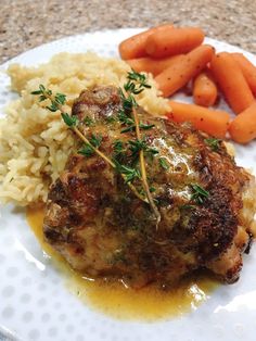 a white plate topped with meat and rice covered in gravy next to carrots