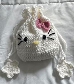 a crocheted hello kitty purse laying on top of a bed