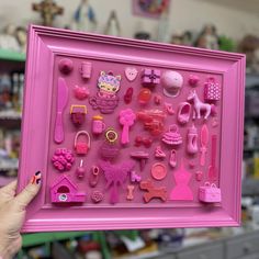 a person holding up a pink frame filled with toys