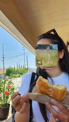 a woman holding a piece of food in her hands and looking at the camera lens