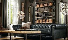 a black leather couch sitting in front of a wooden coffee table next to a book shelf