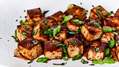 a white plate topped with tofu and green vegetables