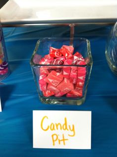 candy in a glass container sitting on top of a table next to a sign that says candy ph