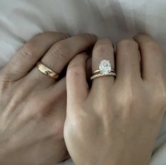 two hands holding each other with wedding rings on top of their fingers and one has a diamond in the middle