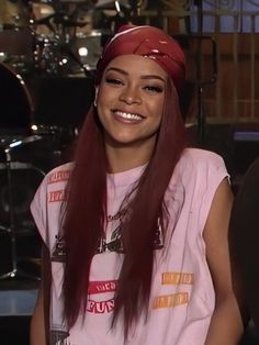 a woman with long red hair sitting in front of a drum set and smiling at the camera