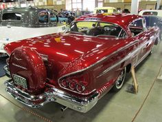 an antique car is on display in a museum with other classic cars and people looking at it