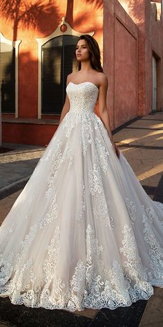 a woman in a wedding dress standing on the sidewalk near a building with palm trees