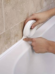 a person using a toilet brush to clean a bathtub with a roll of toilet paper