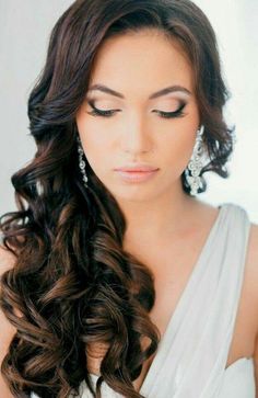 a woman with long brown hair and earrings on her head, wearing a white dress